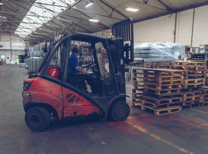 Forklift with driver about to lift a stack of pallets